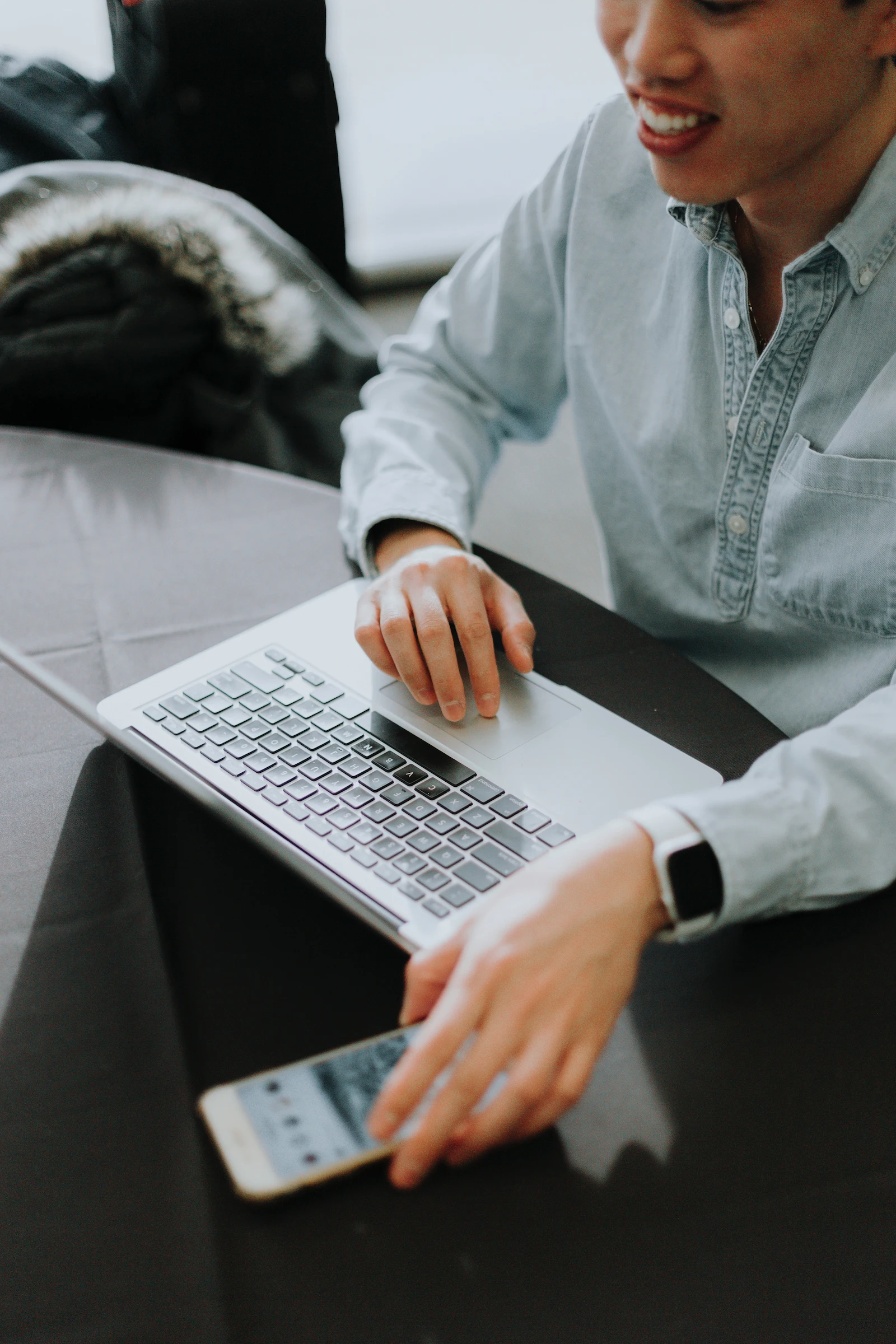 A man sitting with a laptop and a mobile phone